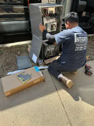 Heating repair in Alexandria VA | HVAC technician assembling outdoor heating unit cabinet prior to installation